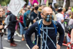 serious adult man in mask near crowd of people